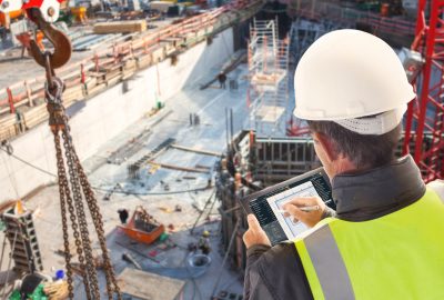 General contractor on consruction site with tablet computer checking building TAKEOFF.